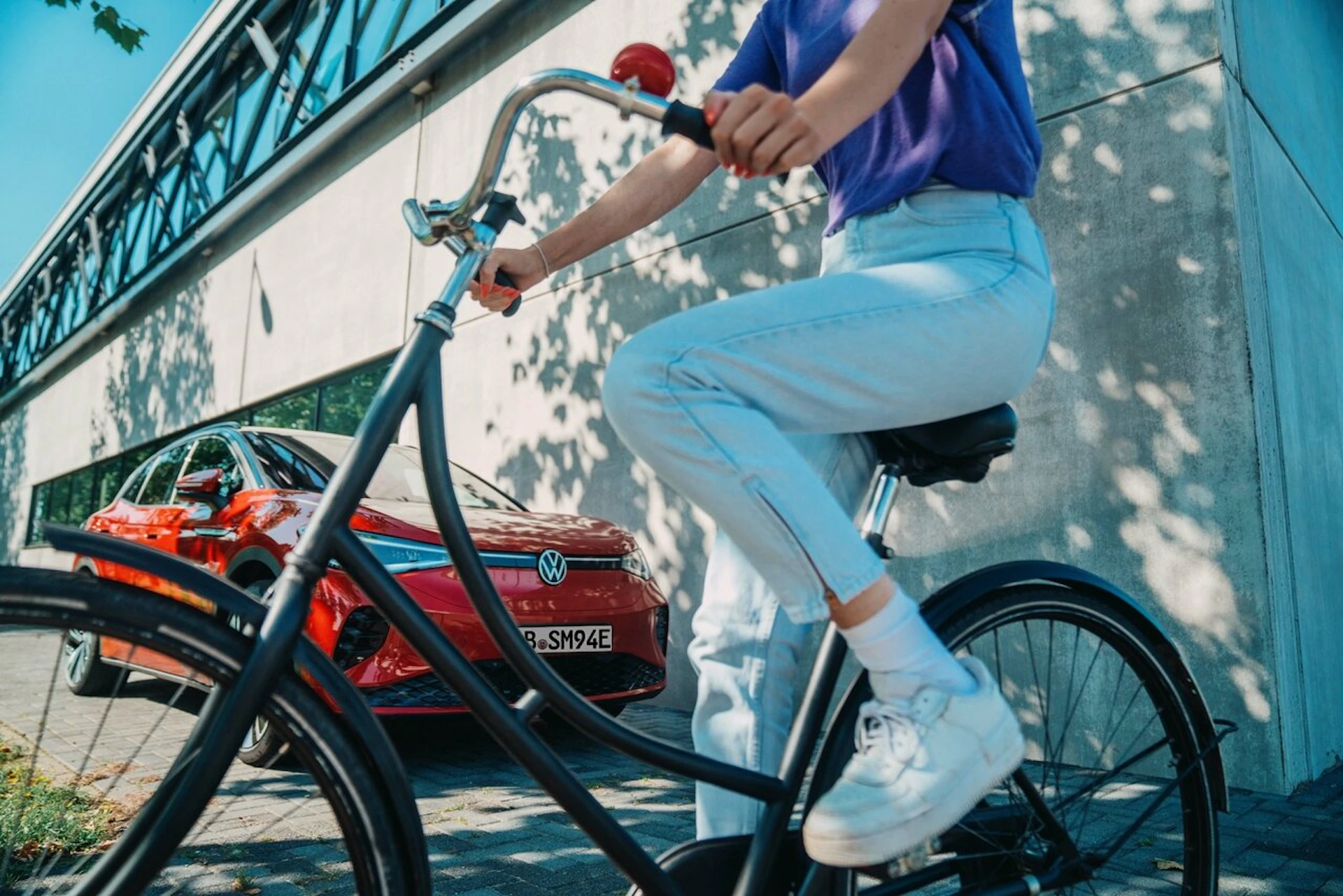 Femme à vélo devant une voiture électrique
