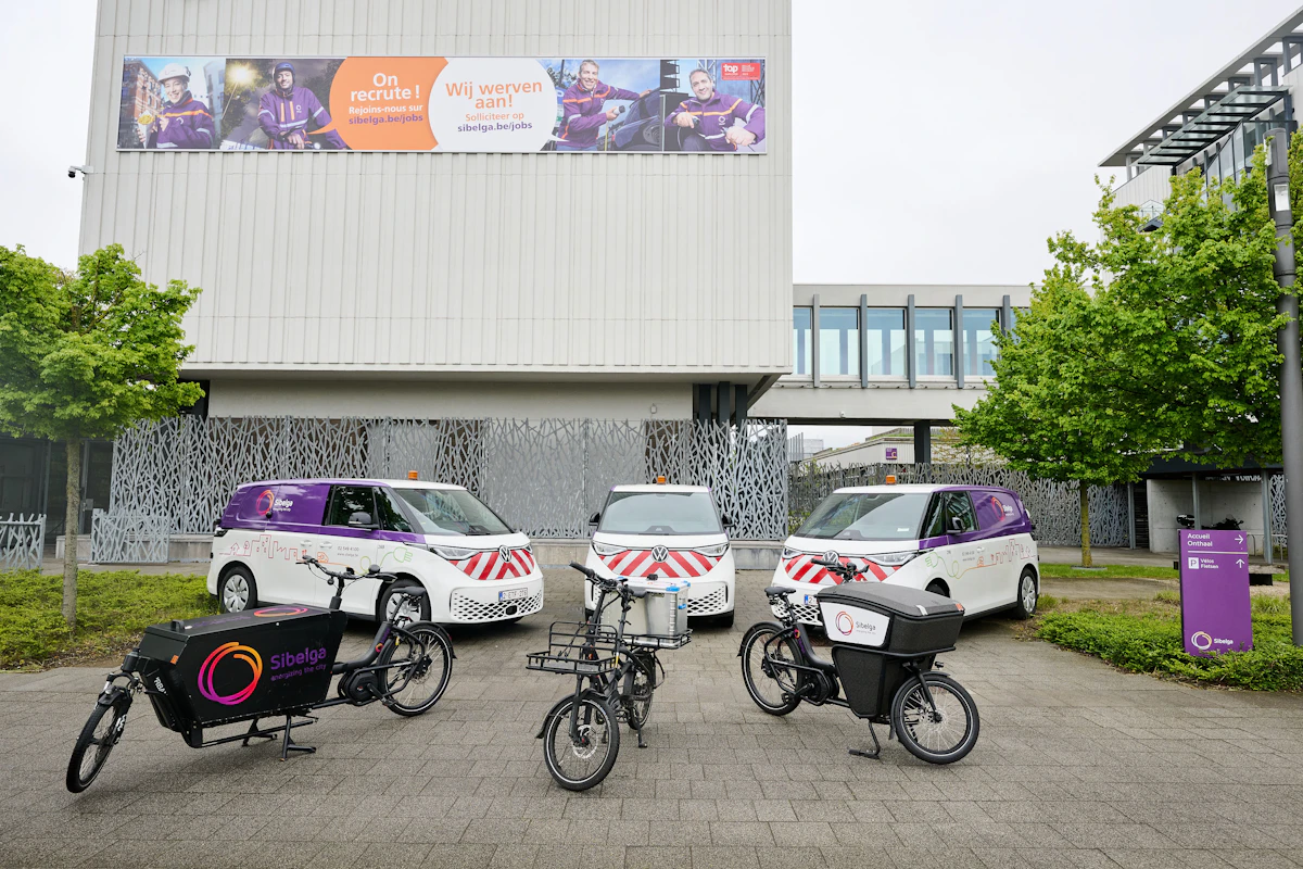 A variety of vehicles Sibelga parked in front of a commercial building